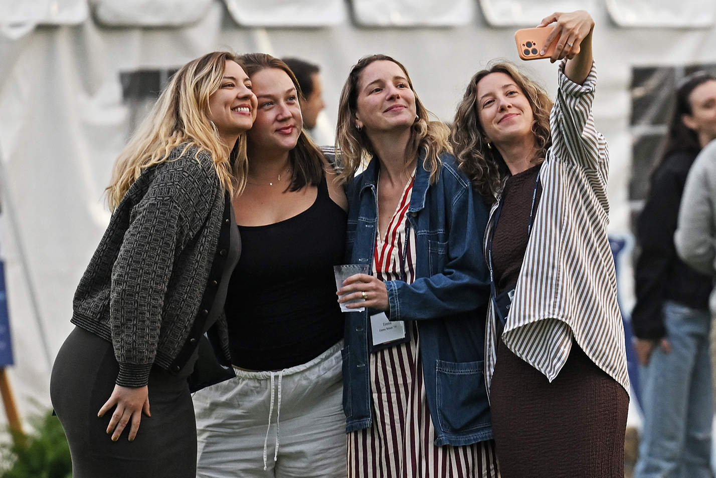 Four female college alumni gather to take a photo as one holds a smart phone camera at arm's length.