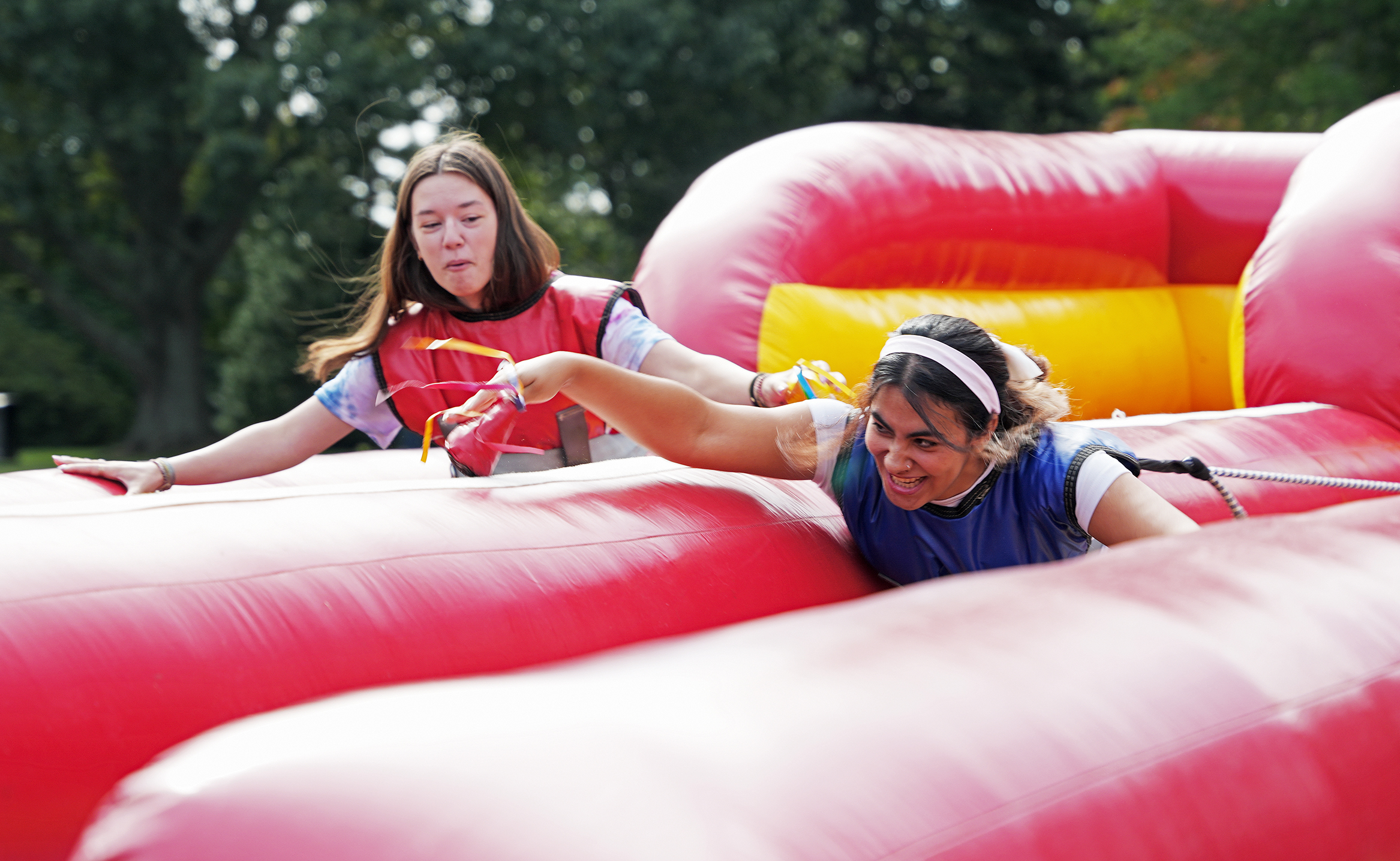 Two female college students race through an inflatable obstacle course.