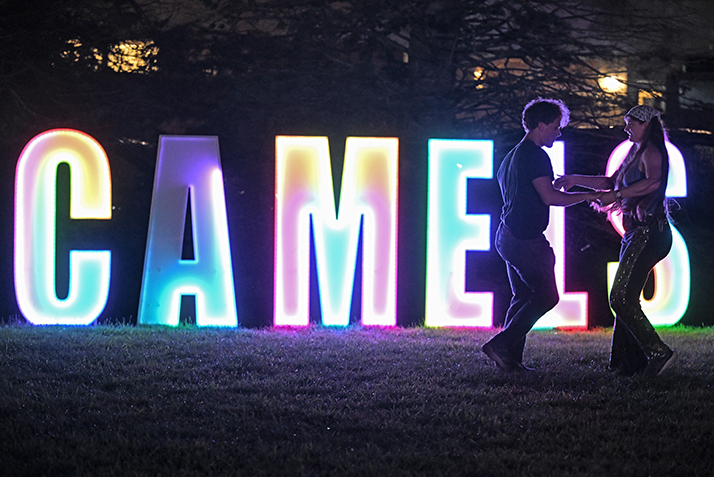 Two students dance in front of a lighted CAMELS sign during the Welcome Weekend Block Party.