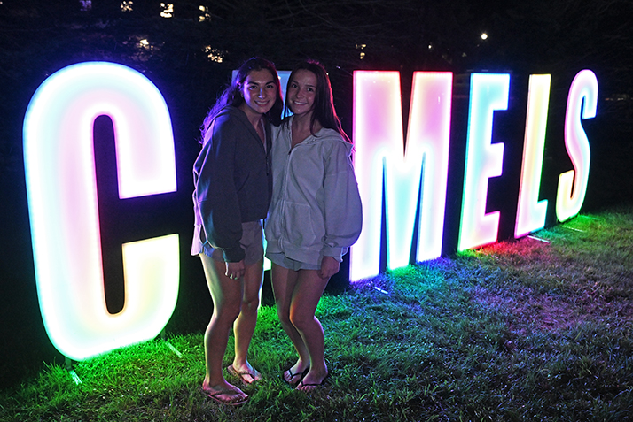 Students pose in front of the lighted CAMELS sign during the Welcome Weekend Block Party.