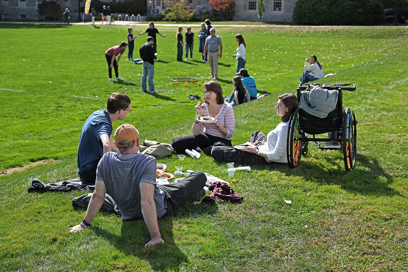 People sit and eat on a college green.