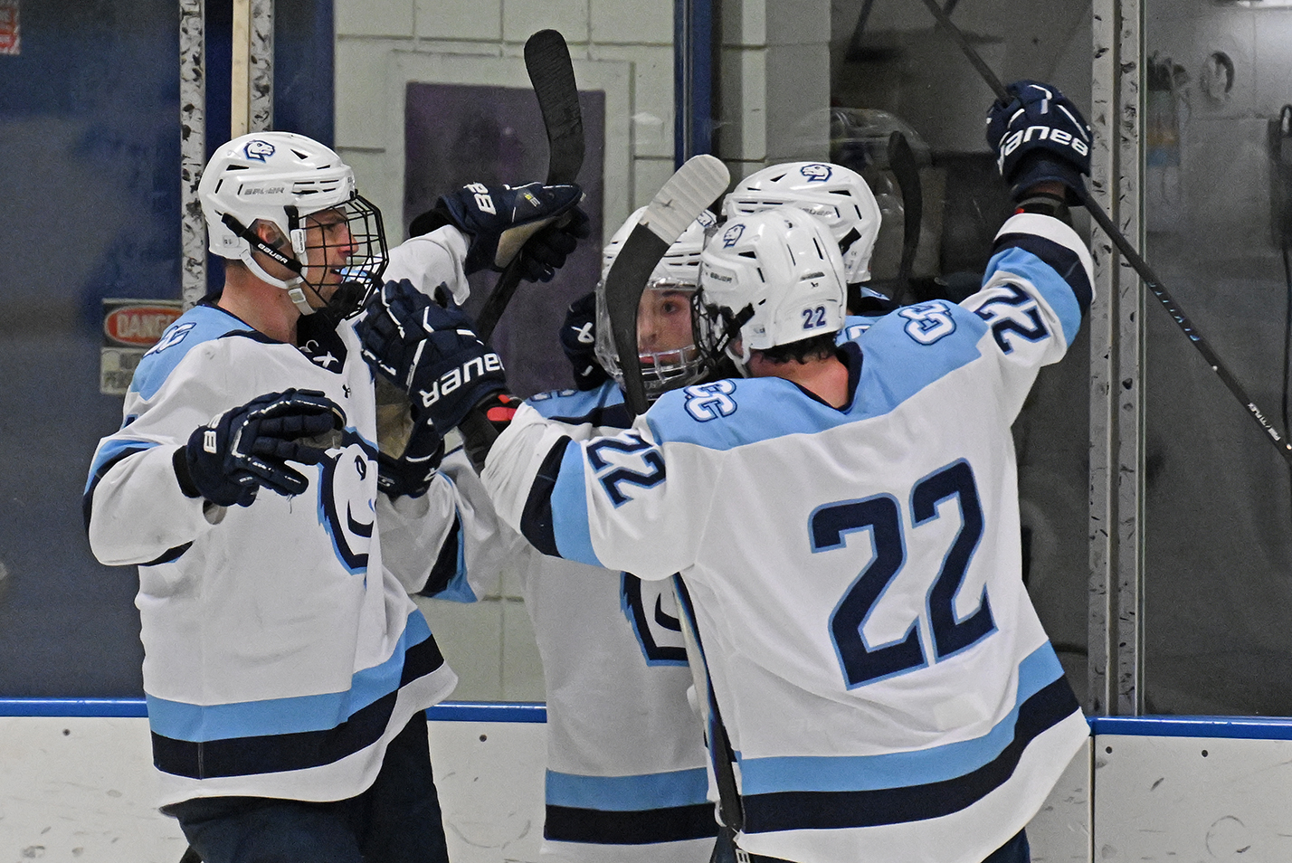 Men's hockey players gather to celebrate a goal.