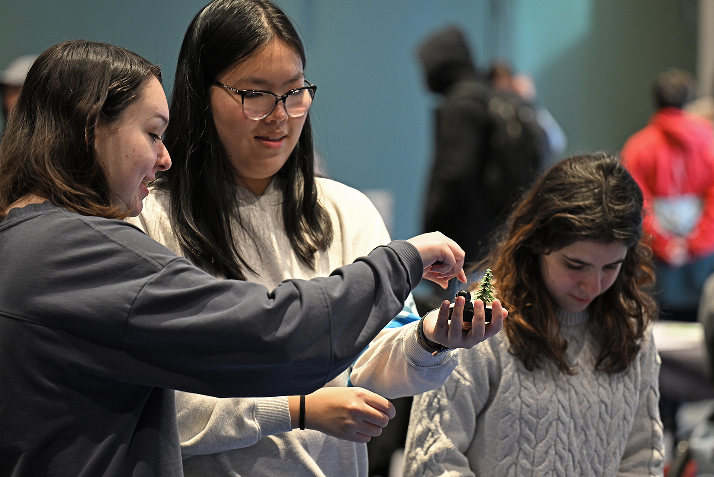 Three female college students work together assembling a winter scene for a snow globe.