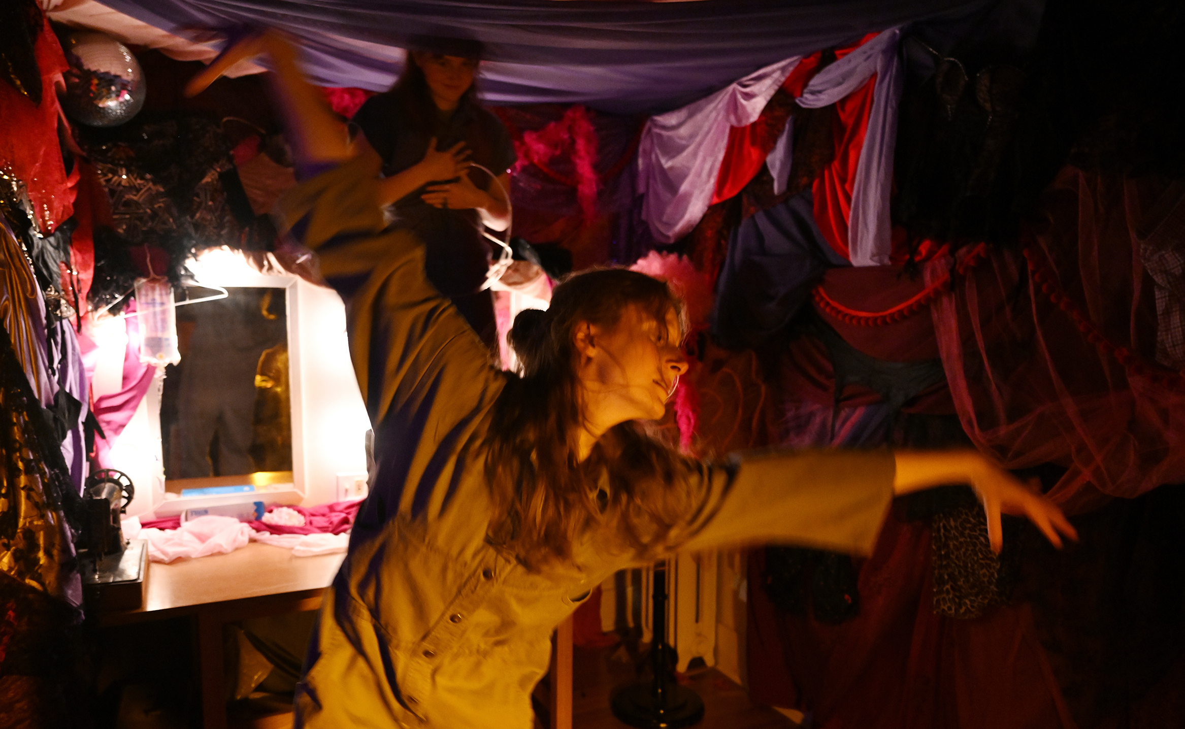 Student dancers perform inside a room with fabric hanging on the walls.