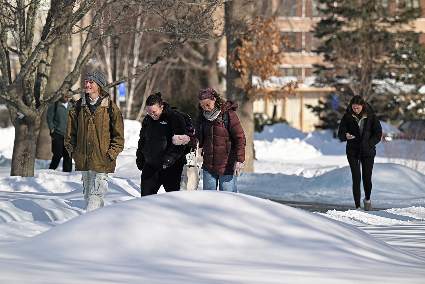 College students make their way through a campus scene blanketing in snow.
