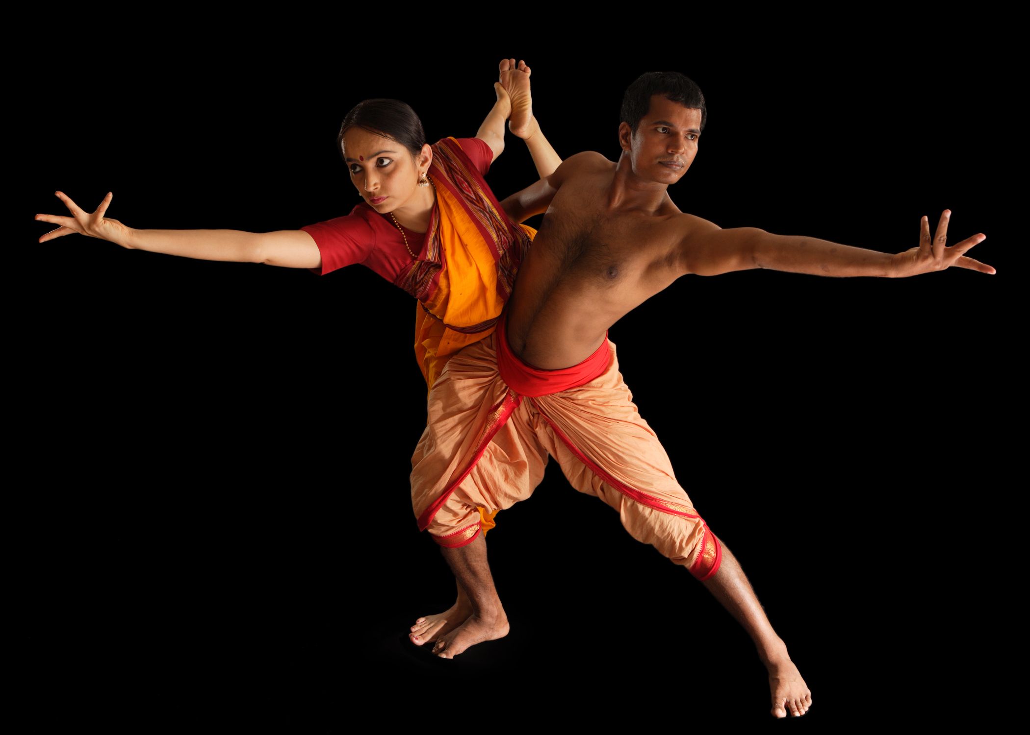 photo of 2 south Asian dancers, one male and one female, in red and gold costumes